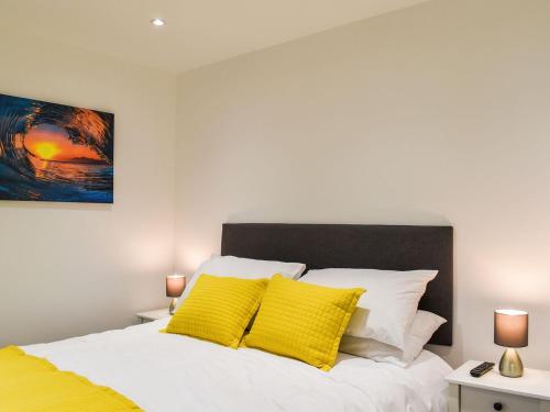 a bedroom with a white bed with yellow pillows at Excalibur Cottage in Saint Annes on the Sea
