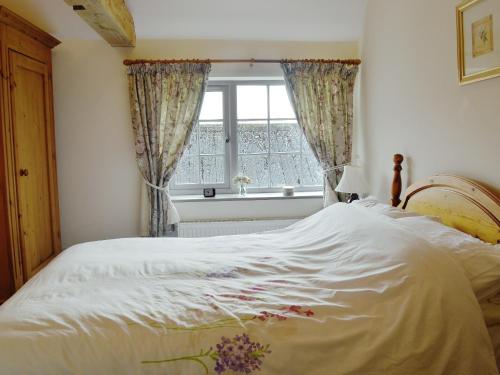 een slaapkamer met een groot wit bed en een raam bij Ostlers Cottage in Long Bennington