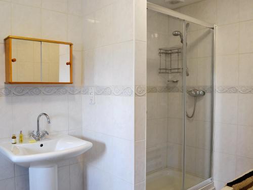 een witte badkamer met een wastafel en een douche bij Ostlers Cottage in Long Bennington
