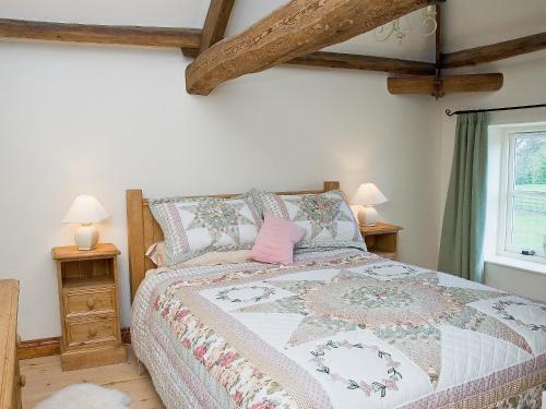 a bedroom with a bed with a pink pillow on it at The Byre - Ijw in Brigham