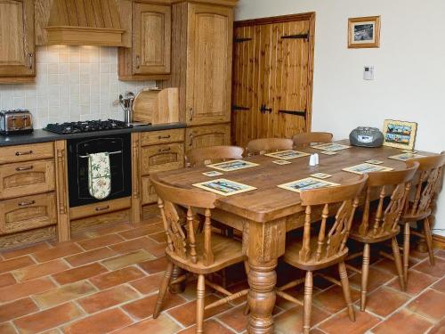 a kitchen with a wooden table and wooden chairs at The Byre - Ijw in Brigham