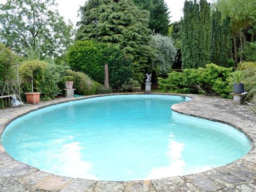 a large pool with blue water in a garden at The Hunting Lodge in Wyck Rissington