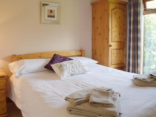 a bedroom with a white bed with towels on it at Oregano - E4483 in Ludham