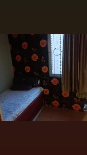 a bedroom with a bed with a flower patterned wall at Apartment Kalibata City by Novi in Jakarta