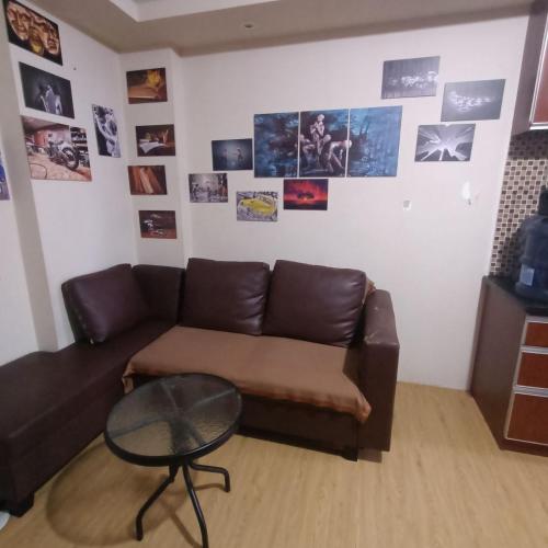 a living room with a brown couch and a table at Apartment Kalibata City by Novi in Jakarta
