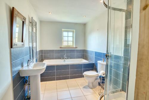 een badkamer met een bad, een toilet en een wastafel bij Pass the Keys Family home in the countryside in Lincoln
