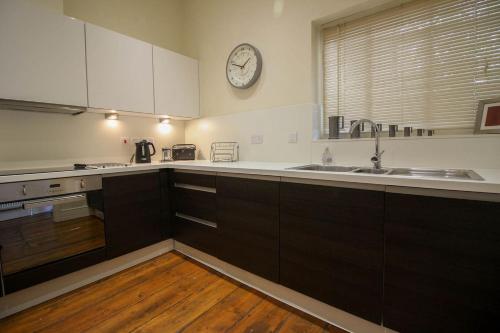 a kitchen with a sink and a clock on the wall at The Old Carriage Works in Lostwithiel