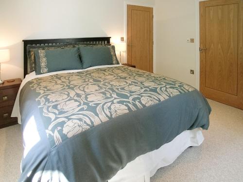 a bedroom with a large bed with a blue comforter at The Barn in Carleen