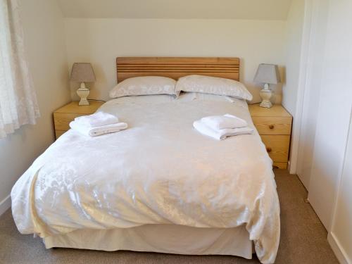 a bedroom with a large white bed with two lamps at Druim-nan-deur in Lochcarron