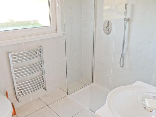 a white bathroom with a shower and a sink at Druim-nan-deur in Lochcarron