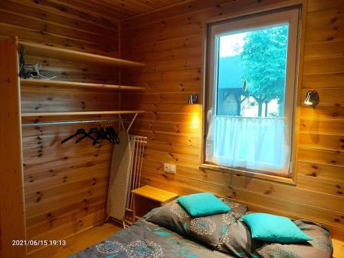 Dormitorio con cama y ventana en una cabaña de madera en Wakacyjne Zacisze, en Rusinowo