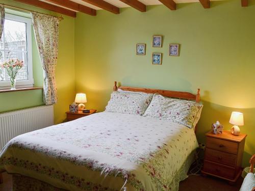 a bedroom with a bed and two lamps and a window at Dyke Heads Stable in Gunnerside