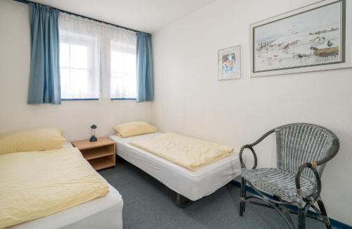 sypialnia z 2 łóżkami, krzesłem i oknem w obiekcie Haus-Frisia-Appartement-402 w mieście Sankt Peter-Ording
