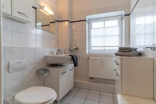 a white bathroom with a toilet and a sink at FeWo-Salzwiesen in Süderhöft