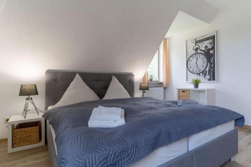 a bedroom with a blue bed with a clock on the wall at Haus Südergeest - Appartement Lio in Tating