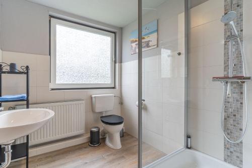 a bathroom with a shower and a toilet and a sink at Haus Südergeest - Appartement Lio in Tating