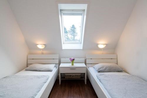 2 Betten in einem kleinen Zimmer mit Fenster in der Unterkunft Haus Angela - Appartement Tom in Sankt Peter-Ording