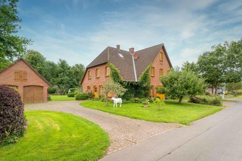 una casa grande con un caballo en el patio en Hohe-Duene, en Vollerwiek