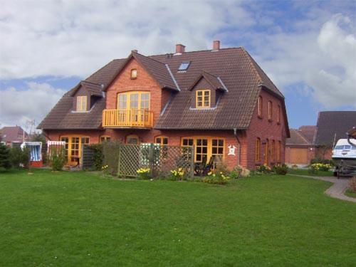 una gran casa de ladrillo con un gran patio verde en Hohe-Duene, en Vollerwiek