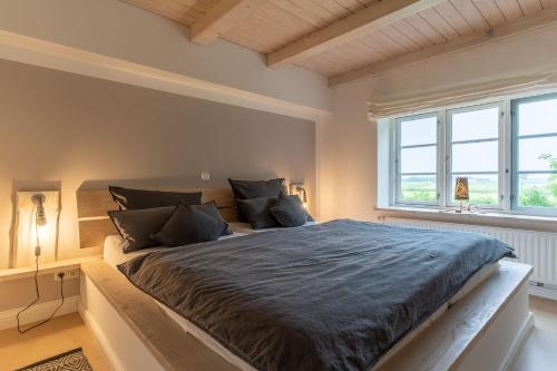 a bedroom with a large bed and two windows at HYGGE-unter-Reet in Westerhever