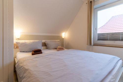een slaapkamer met een groot wit bed en een raam bij Haus-Springfloot-Whg-2-OG in Olsdorf