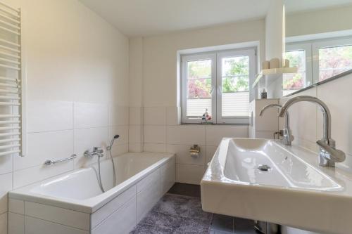 ザンクト・ペーター・オルディングにあるKlein-Friesland-Flutの浴槽と洗面台のある白いバスルーム