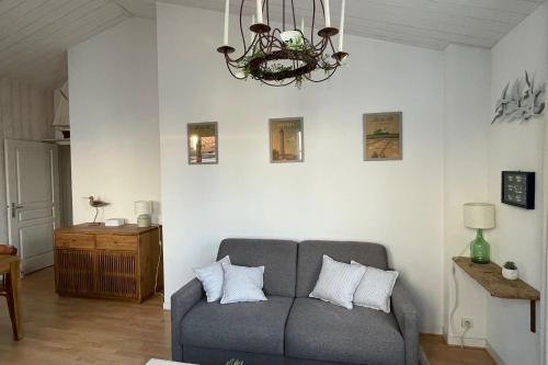 a living room with a couch and a chandelier at Very bright nest with terrace in the village in La Flotte