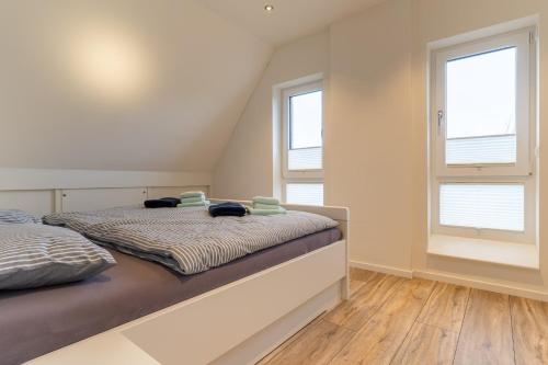 a bedroom with a bed and two windows at Wohnung-Windboee in Sankt Peter-Ording