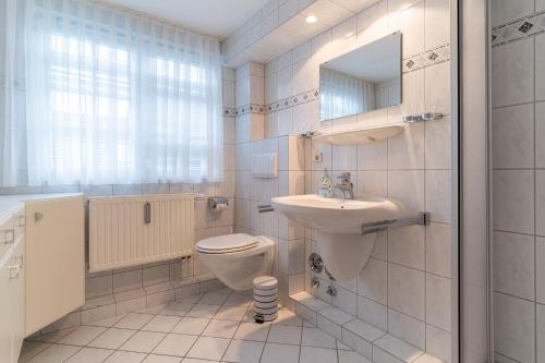 uma casa de banho branca com um WC e um lavatório em Haus-Deichsfenne-App-4-OG em Sankt Peter-Ording