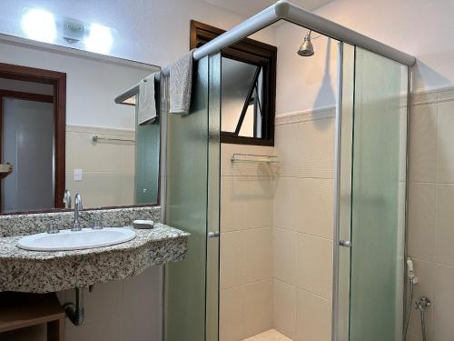 La salle de bains est pourvue d'une douche en verre et d'un lavabo. dans l'établissement Gardel é Destino Floripa Apartamento 2 quartos, à Florianópolis