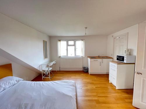 a bedroom with a bed and a kitchen with a window at The great airport place-private bedrooms with private bathroom-1 Bus to Heathrow Airport-5 minutes by car- Helpful advice from our team in Harmondsworth