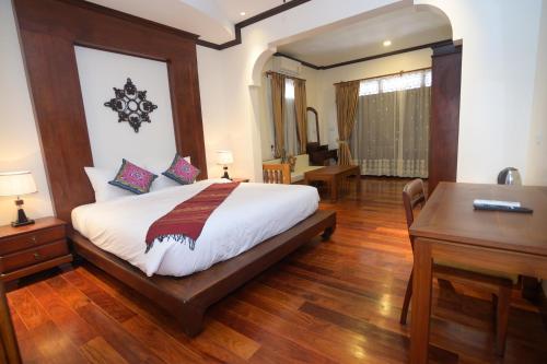 a bedroom with a large bed with a desk and a desk at Lux Hotel in Luang Prabang