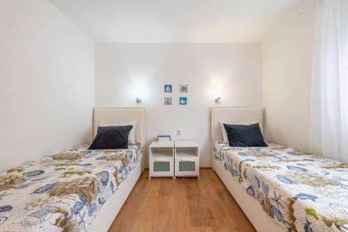 two beds in a room with white walls and wooden floors at Apartmani Luka in Vir