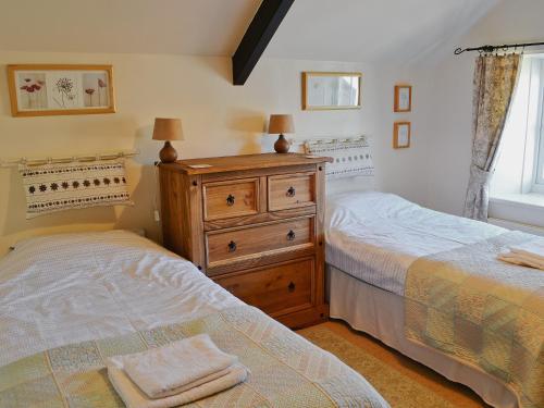 クラスターにあるRowan Cottageのベッドルーム1室(ベッド2台、ドレッサー、窓付)