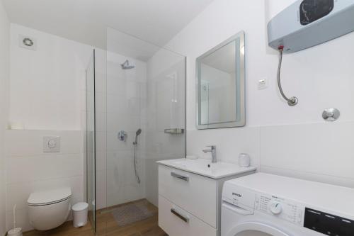 ein weißes Bad mit einem Waschbecken und einer Dusche in der Unterkunft Golden Nin in Nin