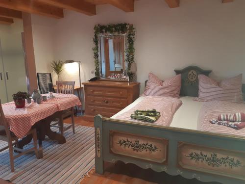 a bedroom with a bed and a table and a mirror at Sonnleit'n Zimmer in Abtenau