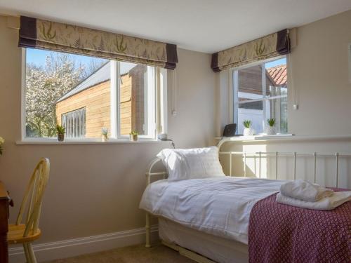 sypialnia z łóżkiem i 2 oknami w obiekcie The Ridings w mieście Thornton Dale