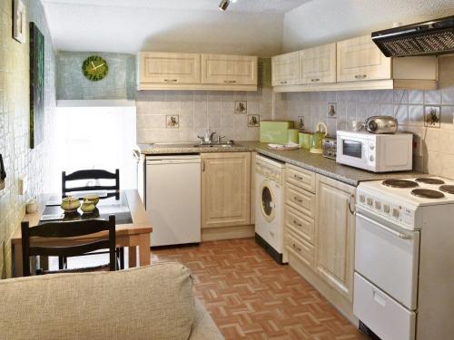 una cocina con electrodomésticos blancos y una mesa. en Gamekeepers Apt - Cv20, en Saint Cleer