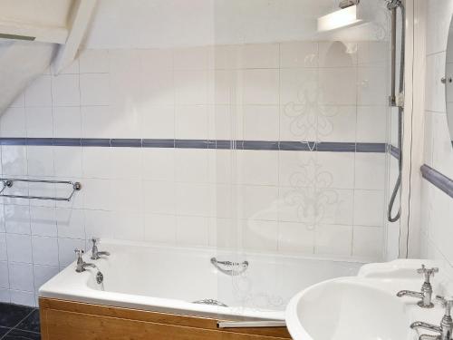 een badkamer met een wastafel en een bad bij Swiss Cottage in Chideock