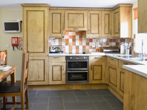 a kitchen with wooden cabinets and a stove top oven at Helygen in Talybont