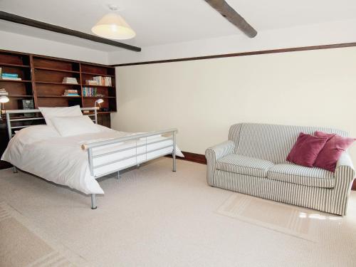 a bedroom with a bed and a couch and a chair at Field Cottage in Sudbourne