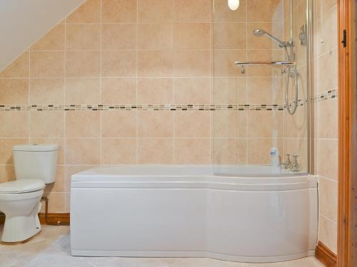 a bathroom with a white tub and a toilet at Hope Cottage in Knighton