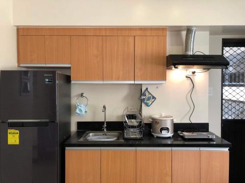 a kitchen with wooden cabinets and a black refrigerator at Camella Northpoint in Davao City