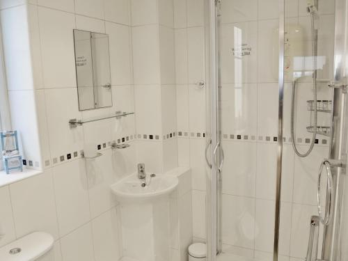 a white bathroom with a shower and a sink at North Shore in Crantock