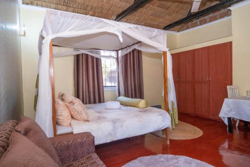 1 dormitorio con 1 cama con dosel en Rudi House en Msaranga