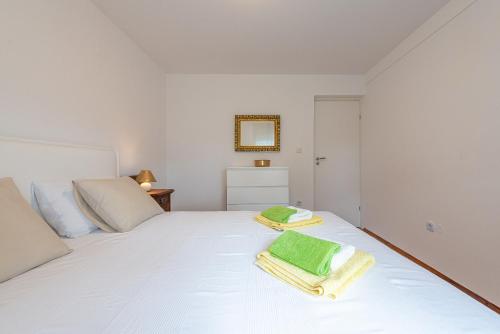a bedroom with a white bed with towels on it at Apartmani Luka in Vir