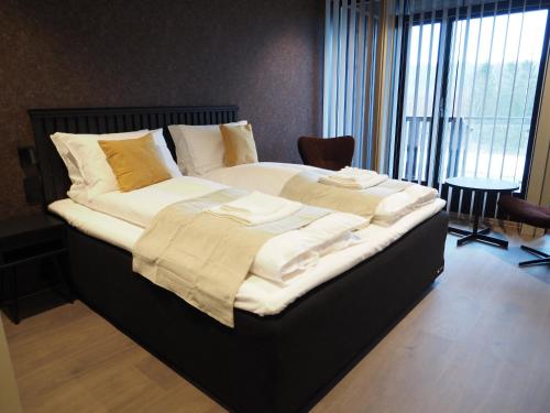 a large bed with white sheets and pillows on it at Hotell Skolestua in Lund