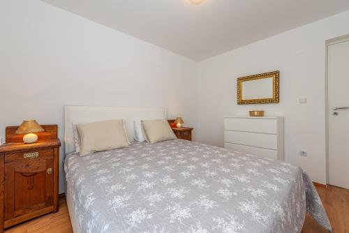 a bedroom with a bed and a wooden dresser at Apartmani Luka in Vir