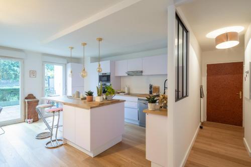 une cuisine avec des armoires blanches et un comptoir dans l'établissement Sérénité - 2 chambres - Calme et Verdure, à Nantes