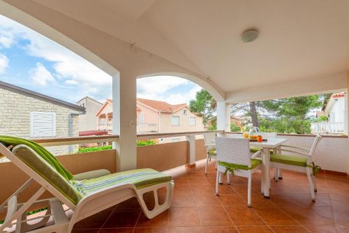 a porch with a table and chairs and a balcony at Apartmani Luka in Vir